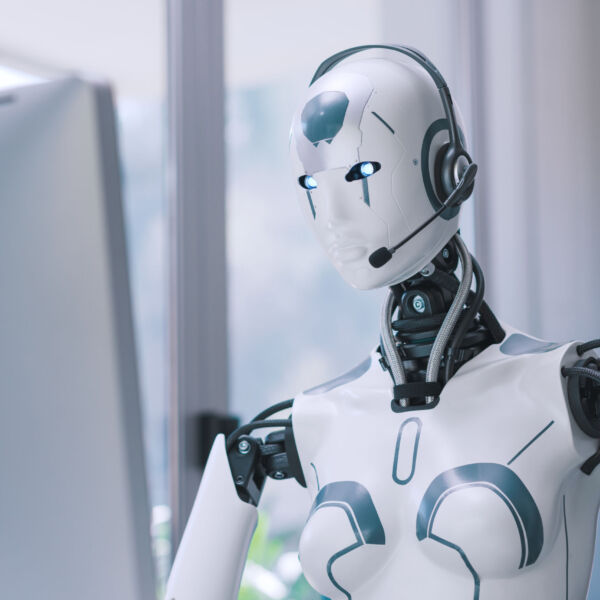 Android AI robot sitting at the desk and working in the office: artificial intelligence, business and automation concept